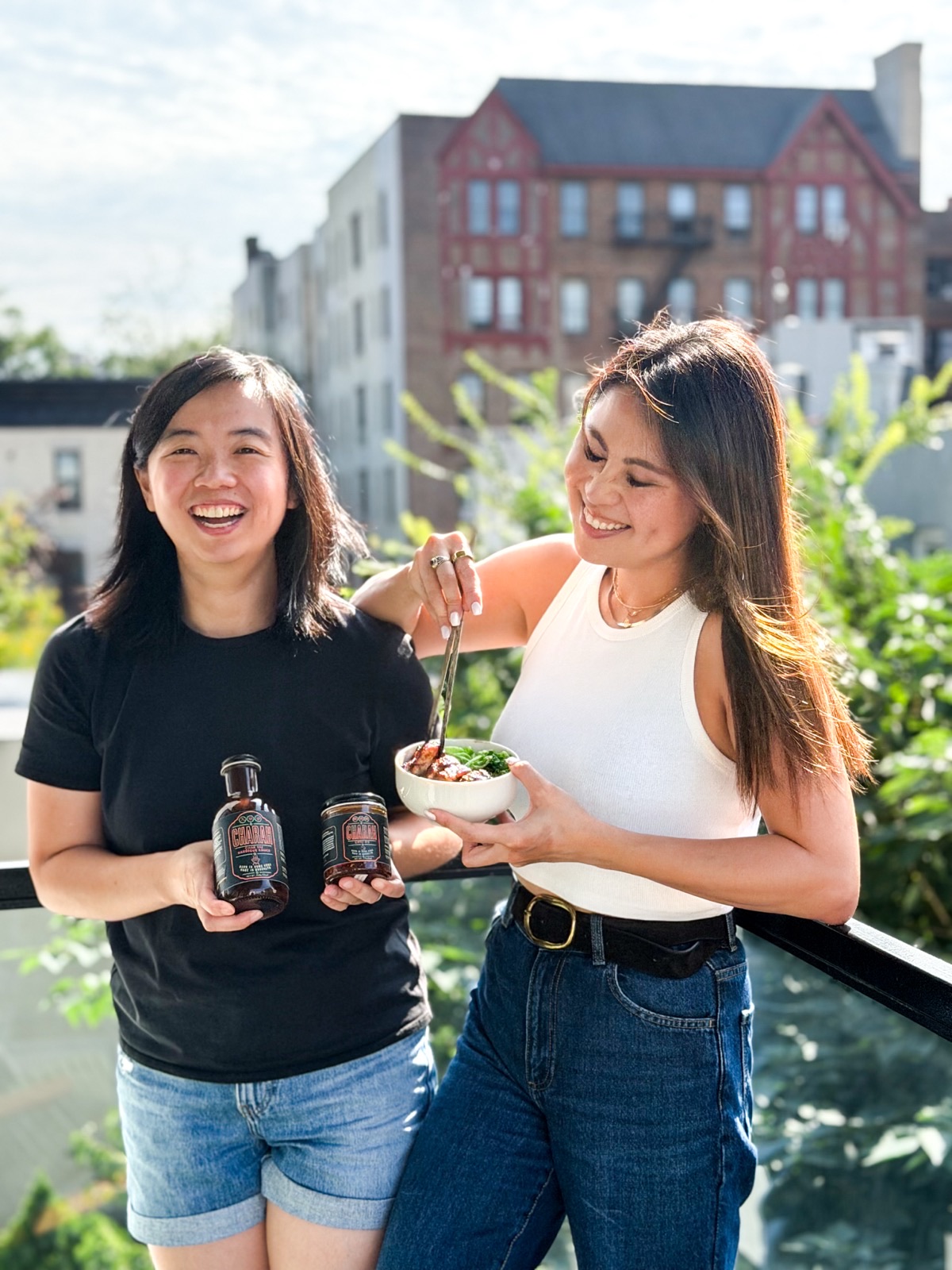 Flora and Clara on a Brooklyn rooftop with a bowl of char siu pork and bottles of Charah sauce